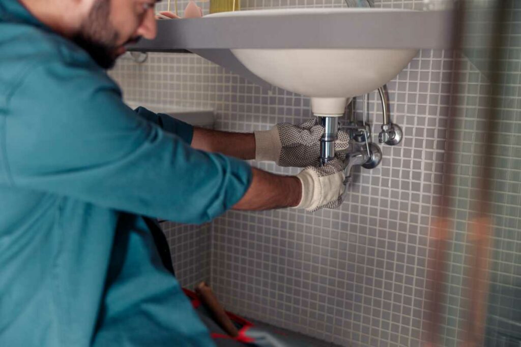 A plumber from your chosen plumbing company, fixing a pipe.