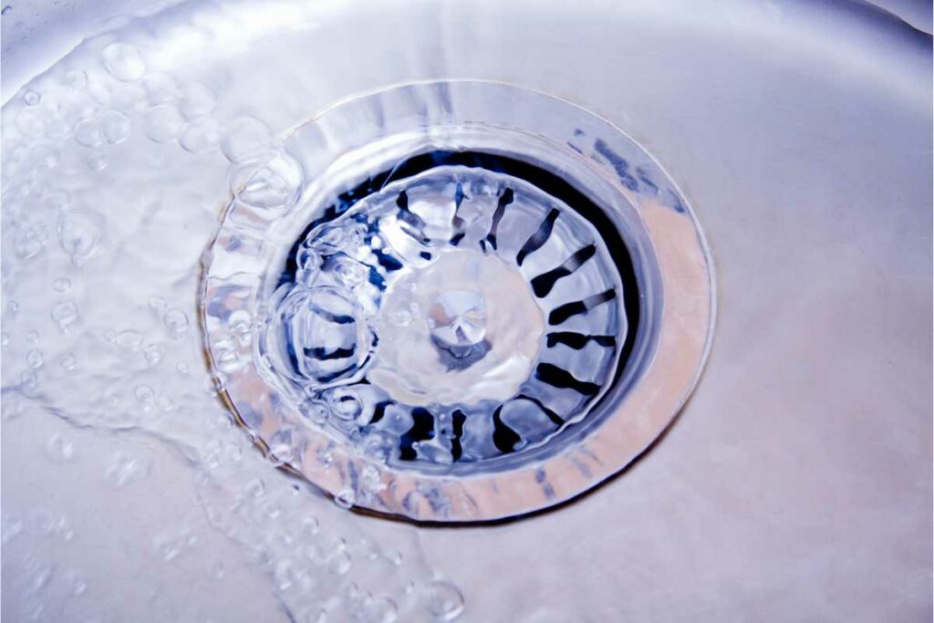 Close-up of a sink drain with water from drain cleaning