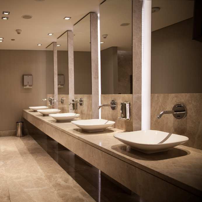 Commercial restroom with a row of sinks, faucets, and mirrors.