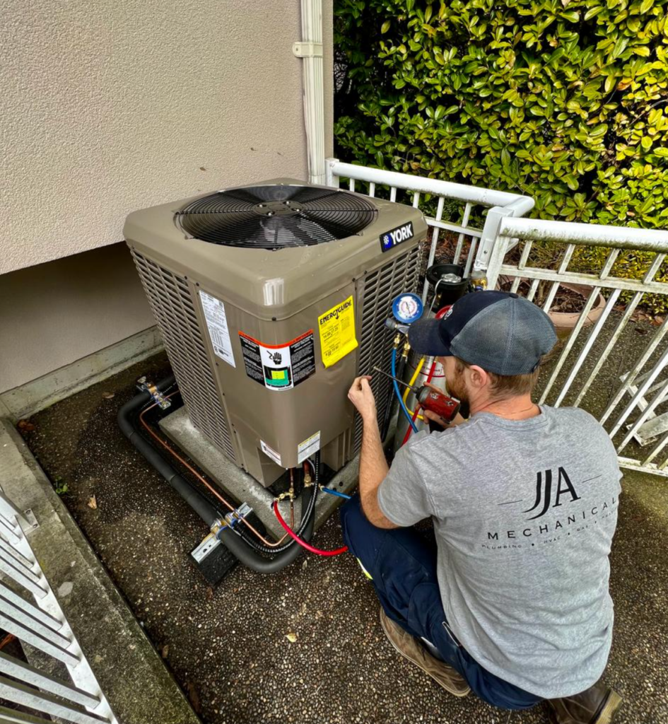 Dylan from JJ&A Mechanical using a drill to finish a new heat pump installation.