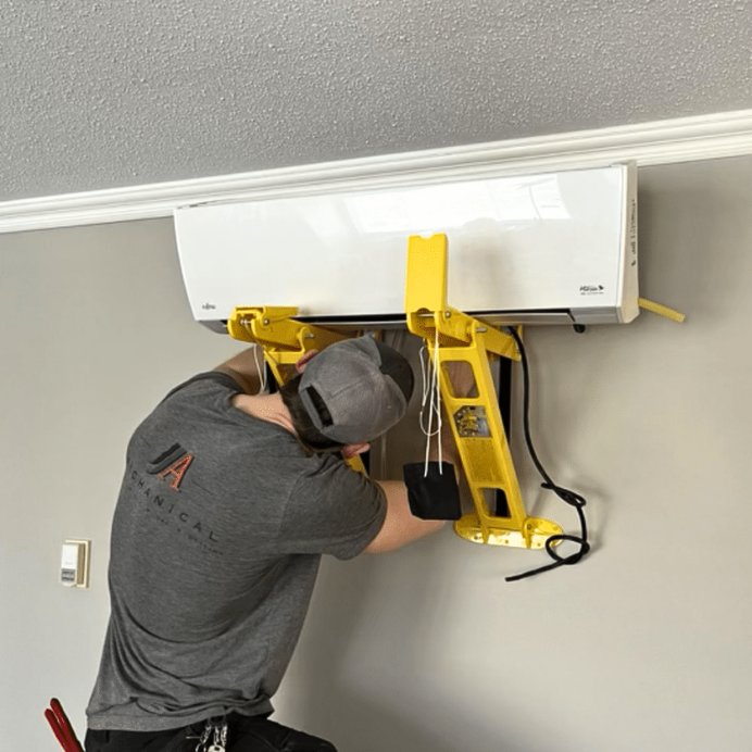 Tech installing air conditioning unit to homes wall