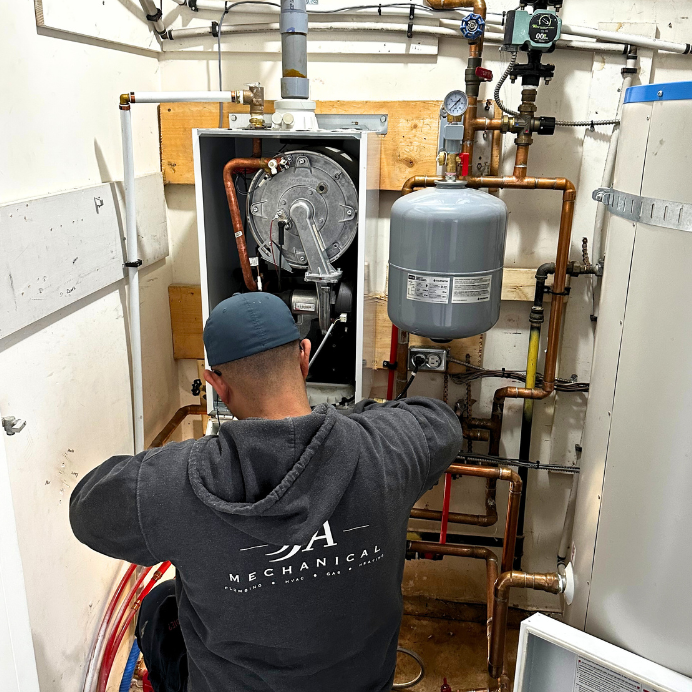 Expert plumber wearing JJ&A Mechanical's uniform working on plumbing & hvac system